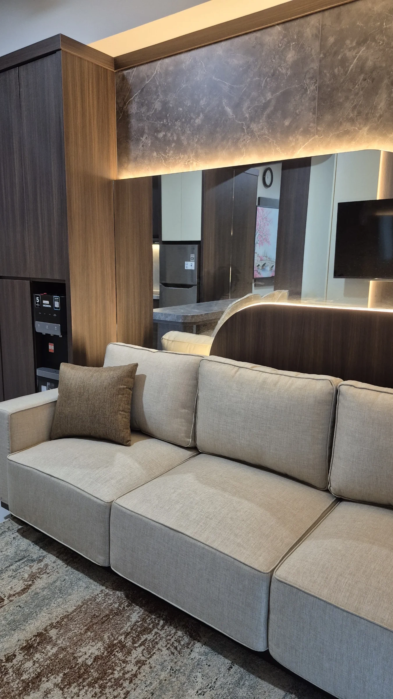 Sofa abu-abu dengan dinding batu berlampu LED dan panel kayu di ruang apartemen