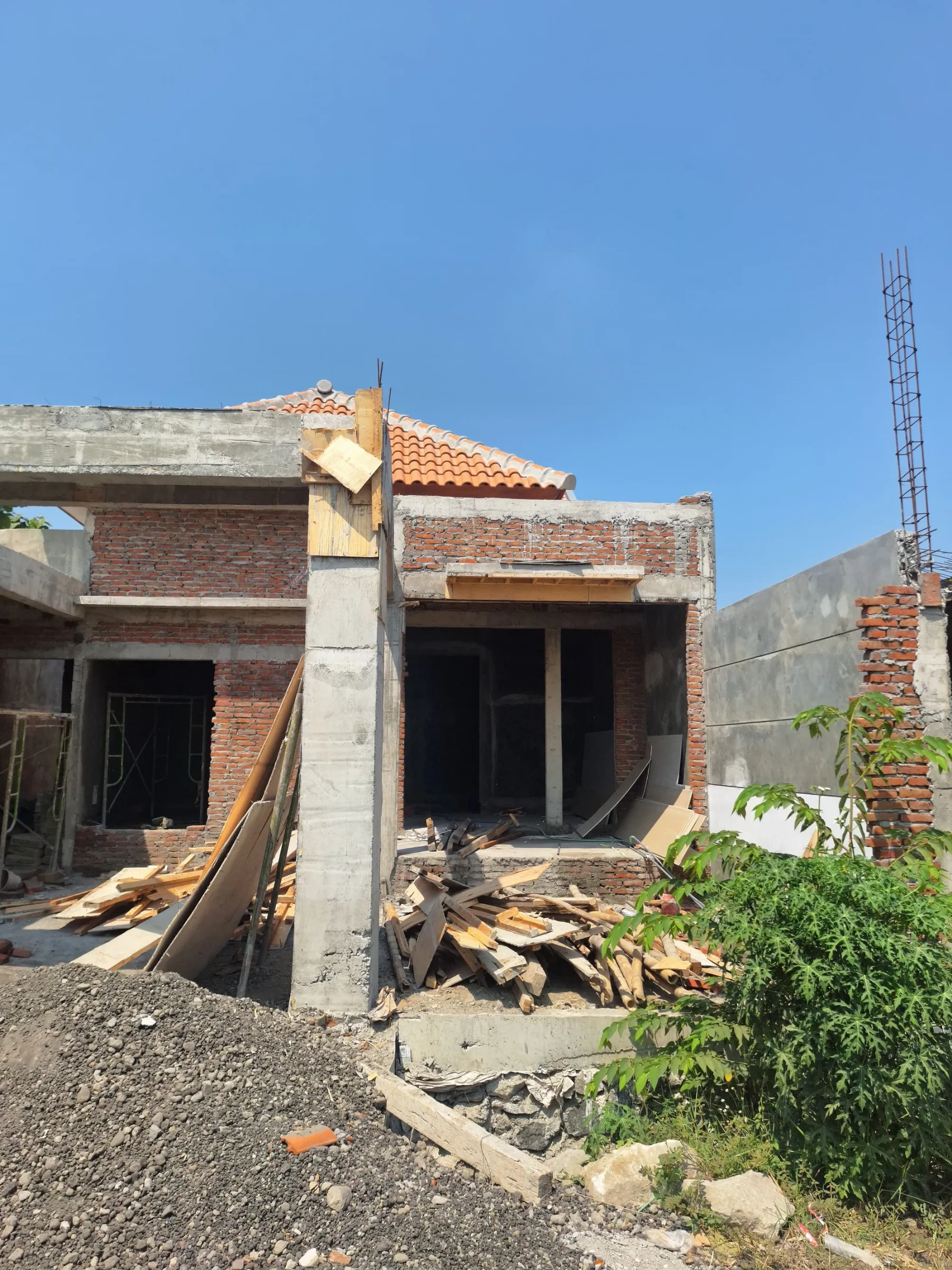 Bangunan rumah dengan dinding bata, kolom beton, dan atap genteng pada tahap struktur